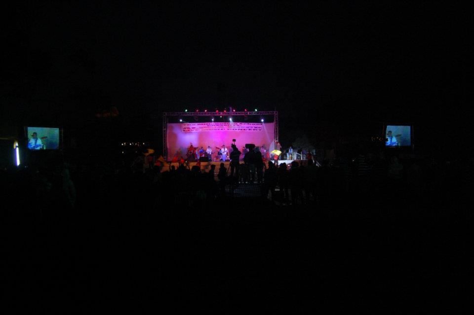 Crowd facing a brightly lit concert stage during a live music performance