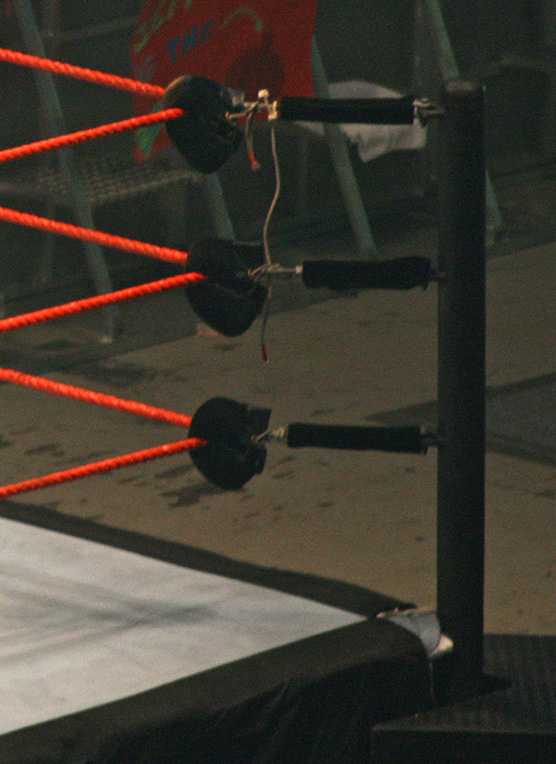 Wrestling-ring ropes and turnbuckles under arena lights