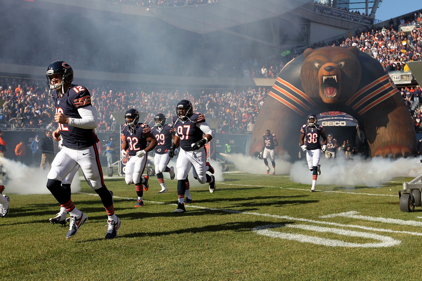 Chicago Bears players run onto the field through smoke at Soldier Field