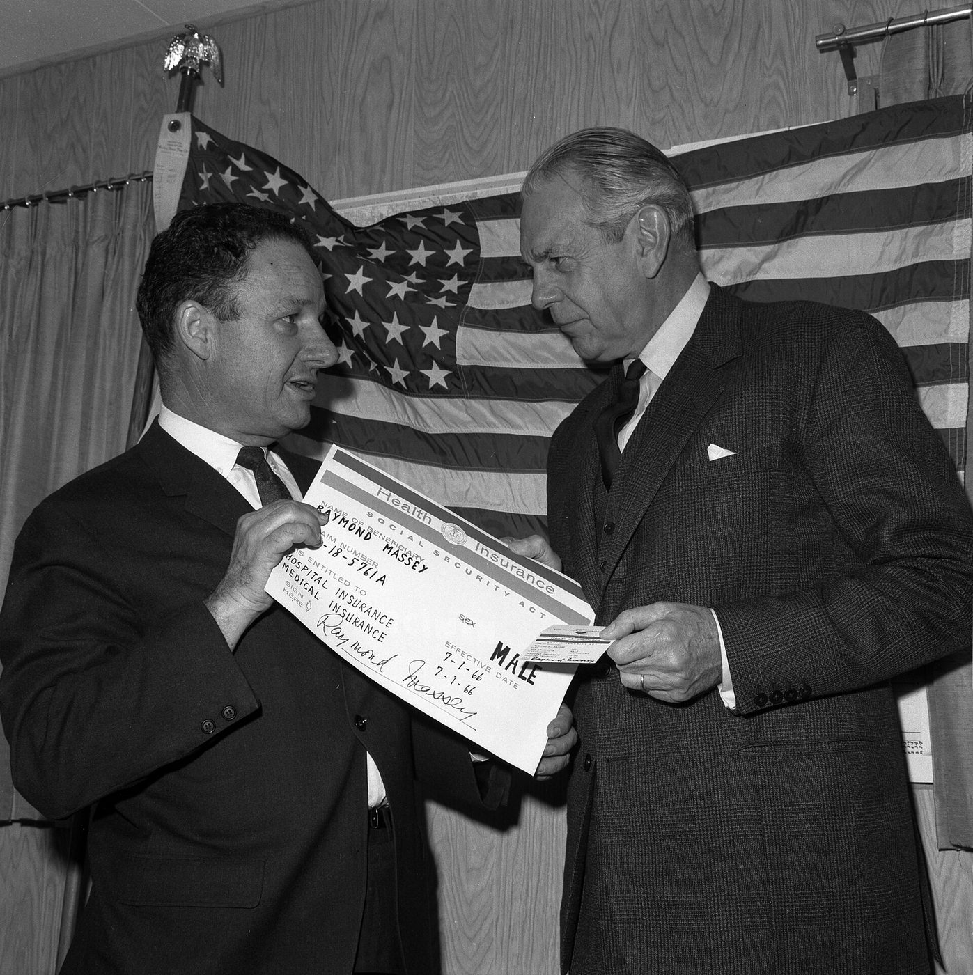 Actor Raymond Massey receives the first Medicare identification card