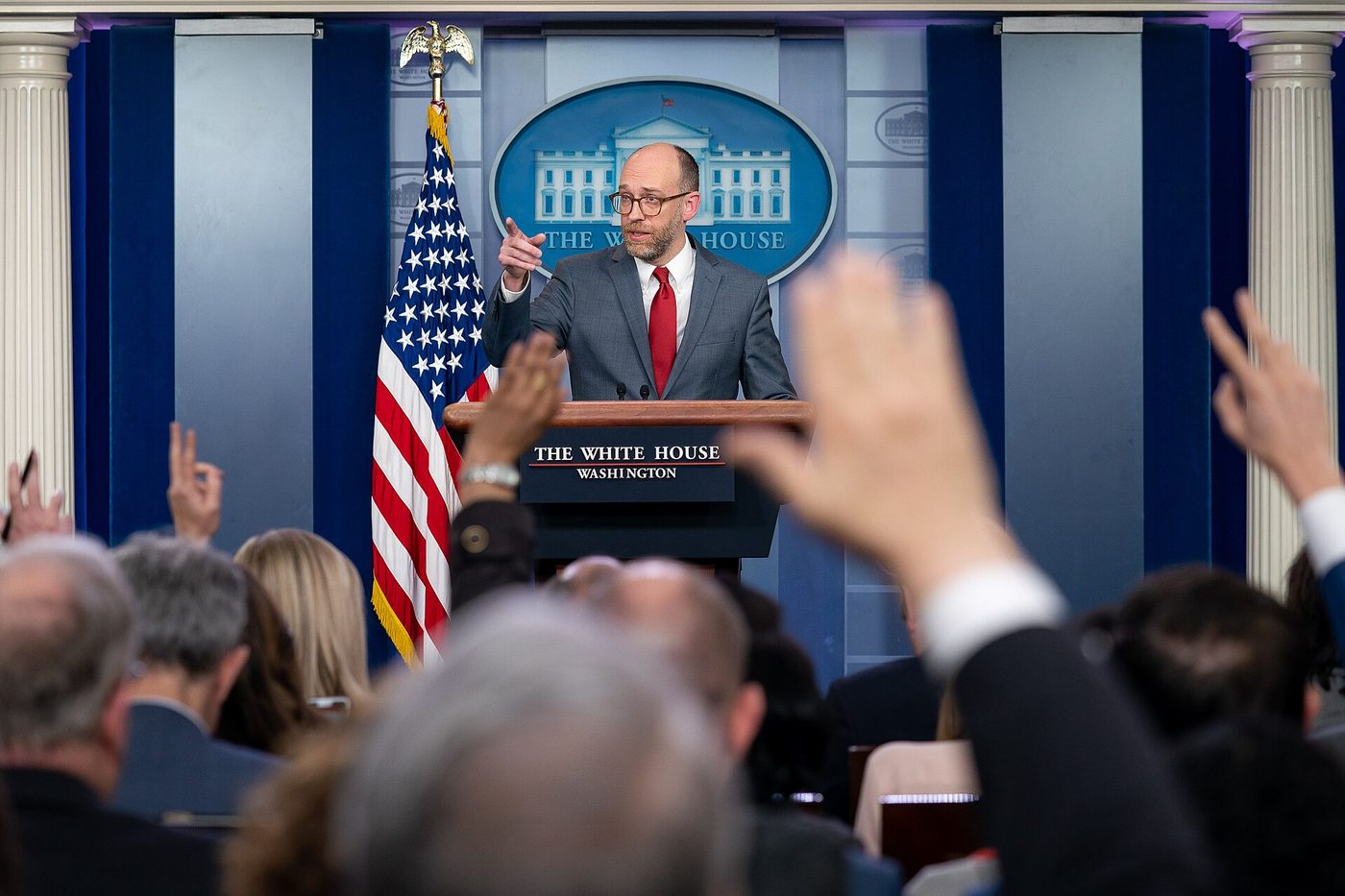 Reporters raise their hands to ask questions at a White House press briefing