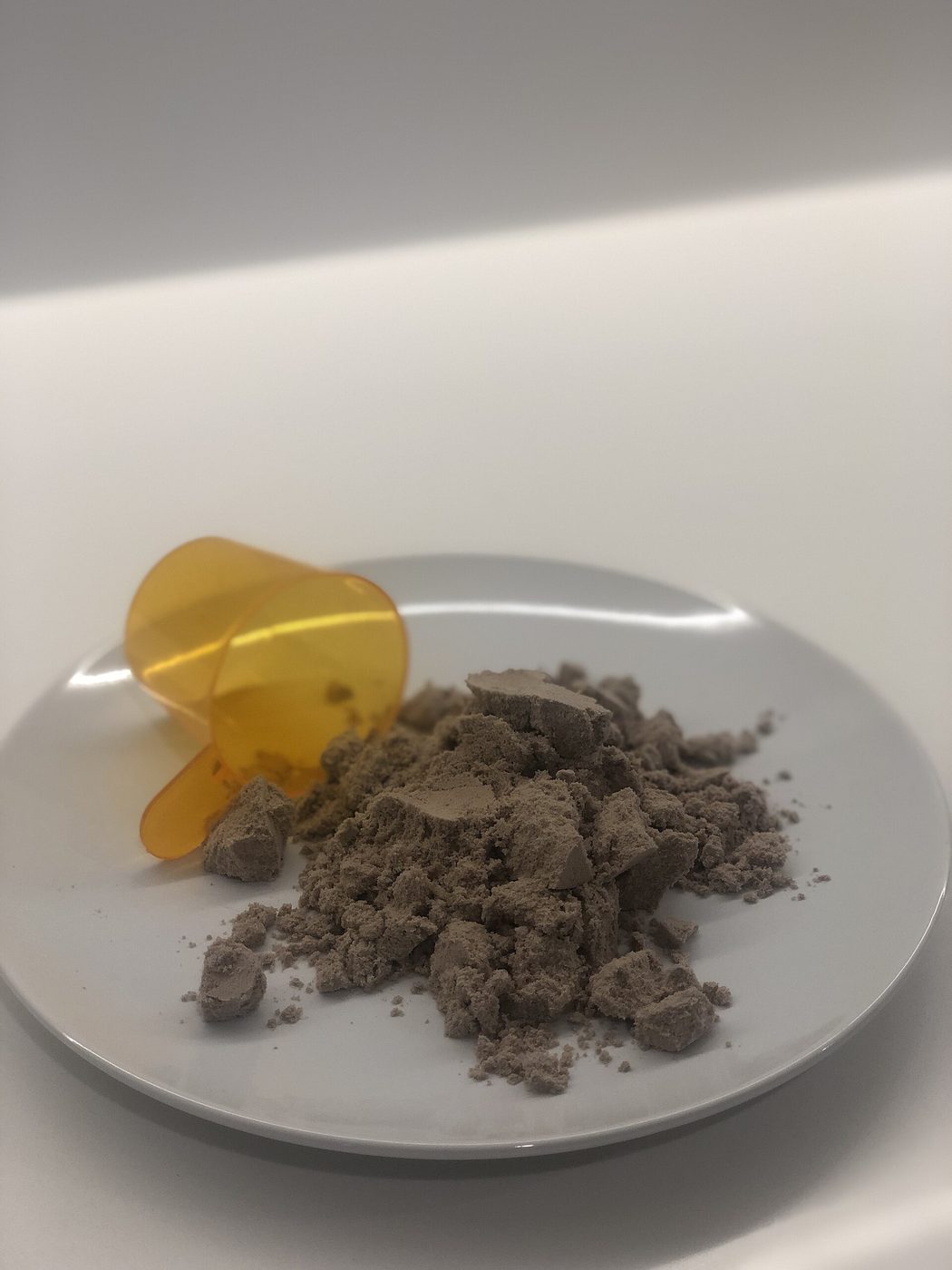 Chocolate-flavored pea protein powder with its serving scoop