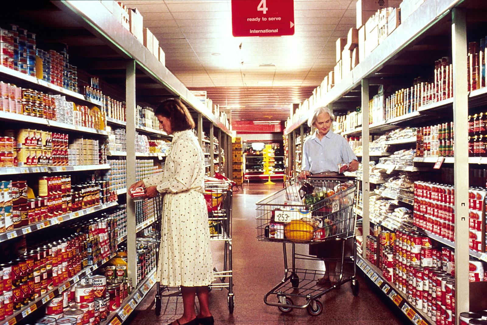 Two women with grocery carts shopping in a supermarket