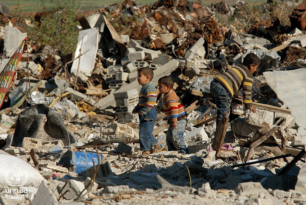 Archival photo of boys salvaging material from a destroyed building in the Gaza Strip