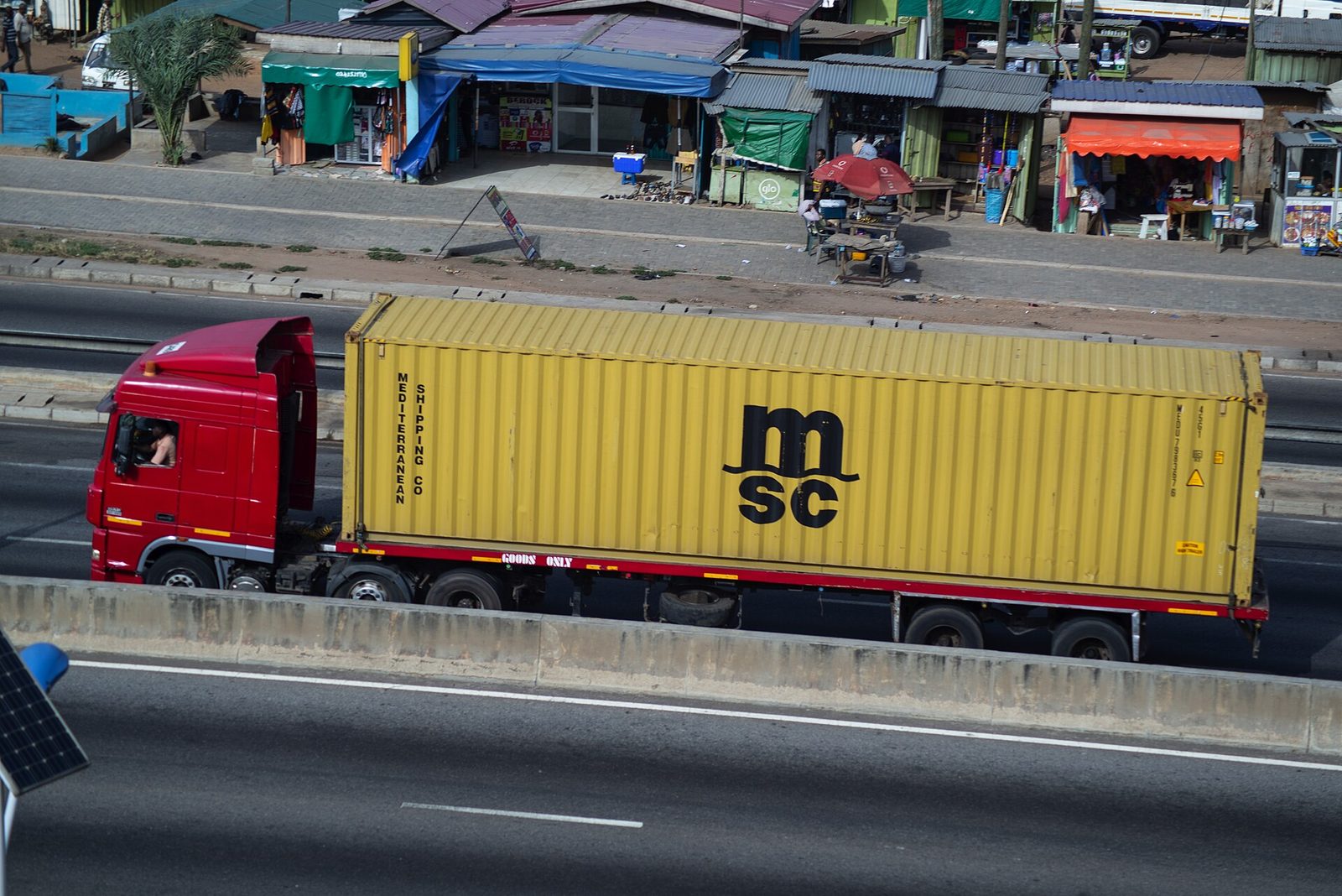 A tractor-trailer truck carrying a shipping container