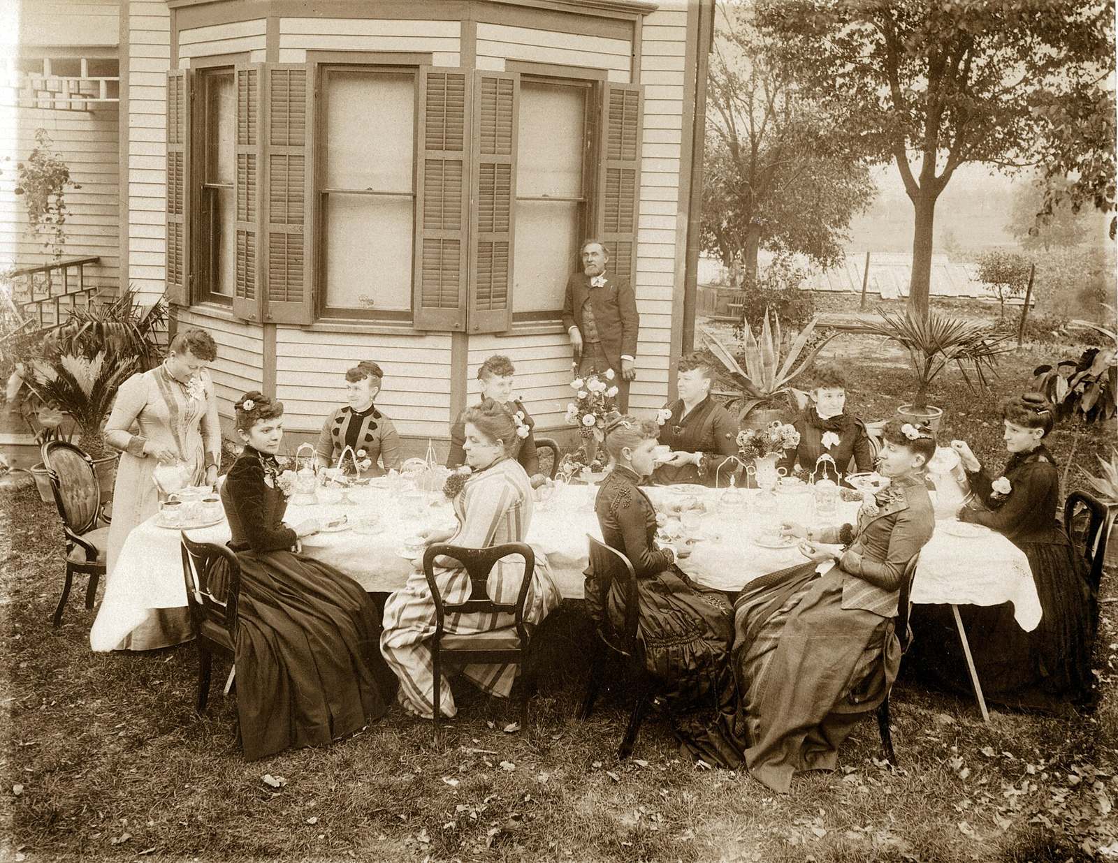 Friends having coffee in a backyard, in an archival photo