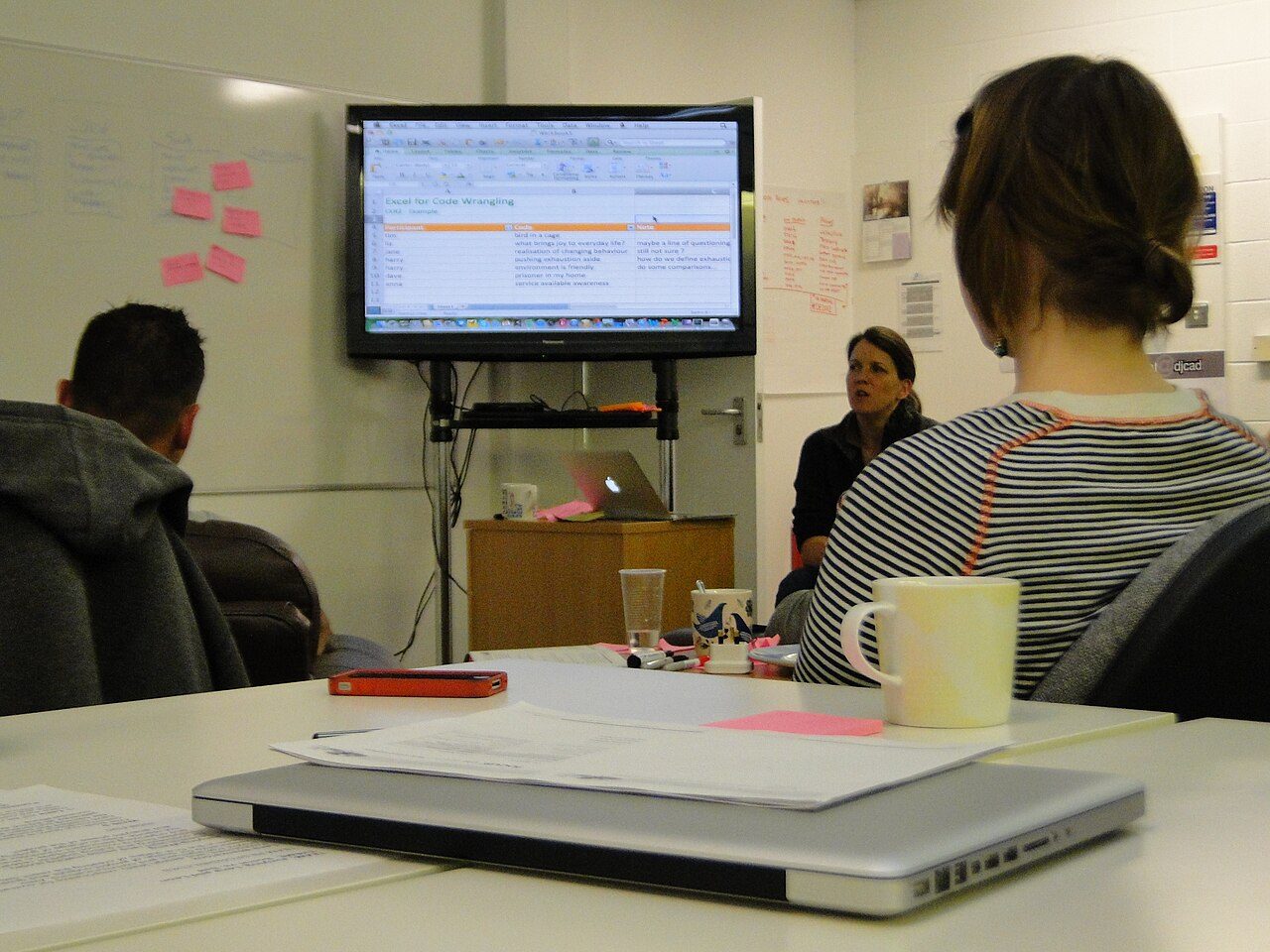 People reviewing data on a large screen with a laptop in the foreground