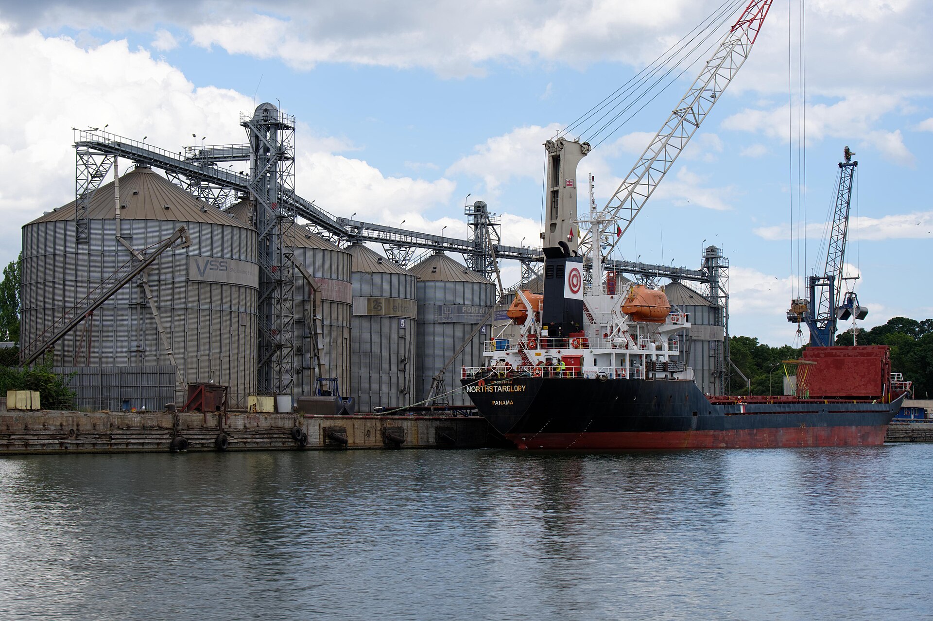 A cargo ship moored beside grain silos and cranes in the port of Varna, Bulgaria