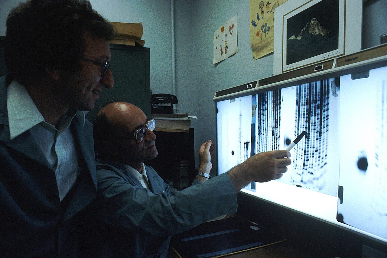 Two scientists in lab coats working with DNA sequencing equipment