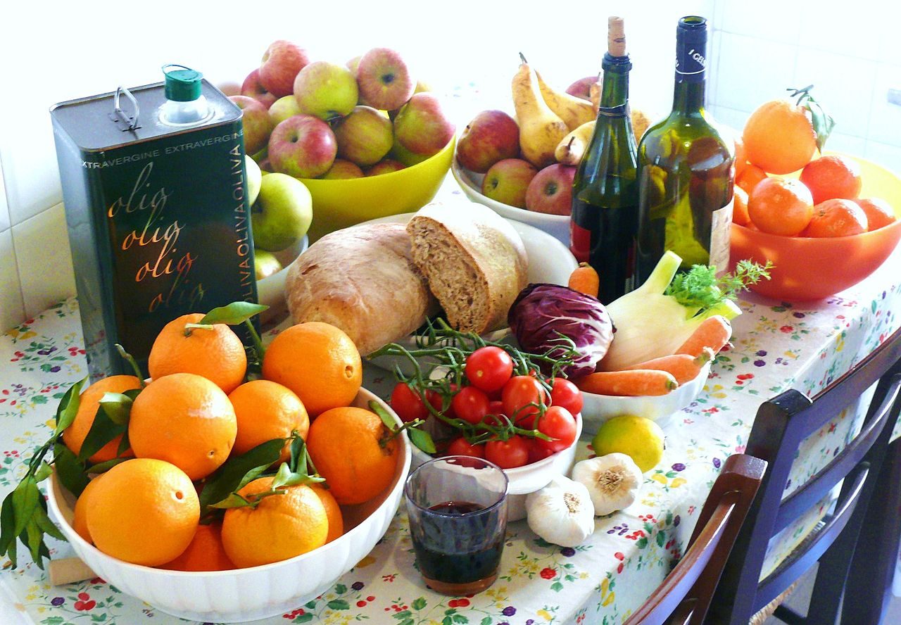 A table of Mediterranean foods including vegetables, bread, cheese and olive oil