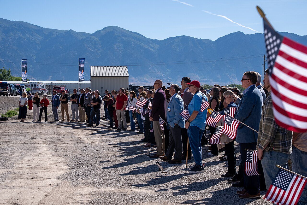 People holding American flags at an outdoor ceremony in Utah for the Artemis III booster shipment