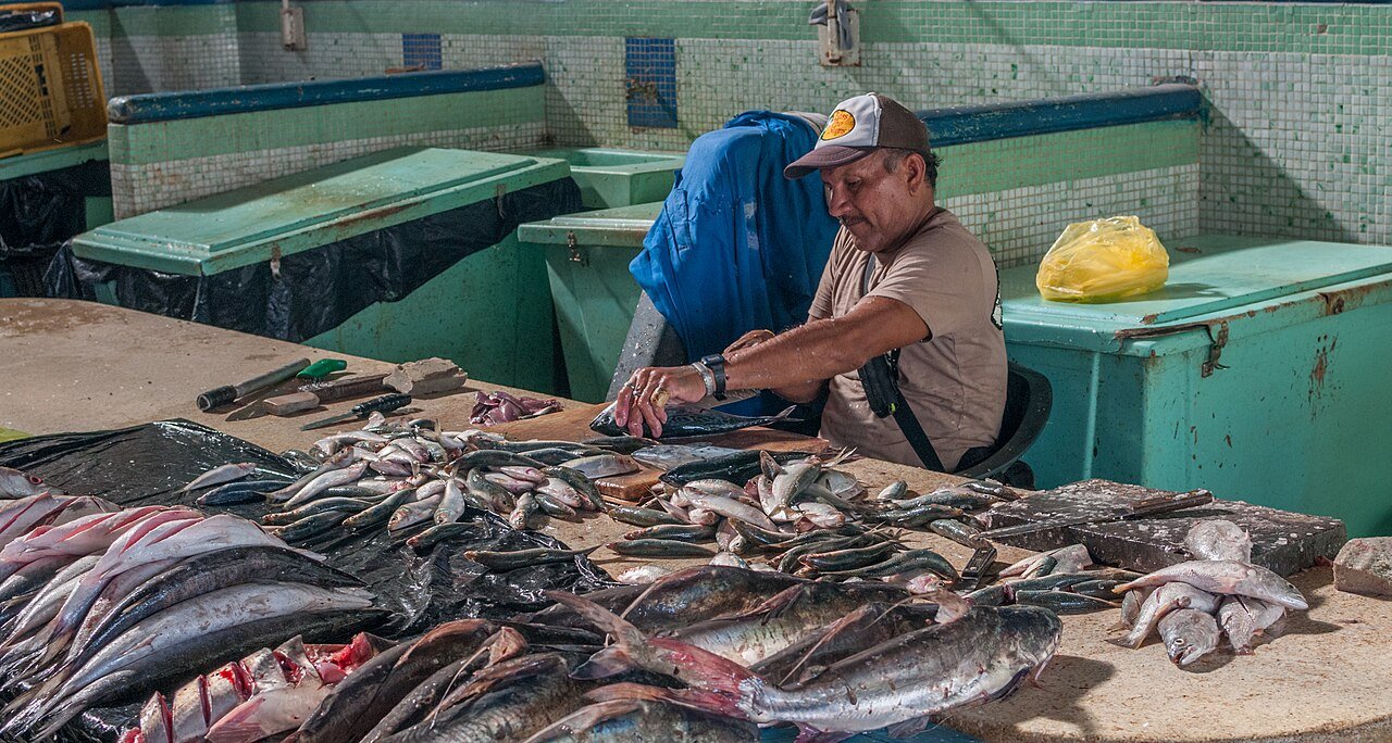 A fishmonger cleaning fresh fish at a market stall