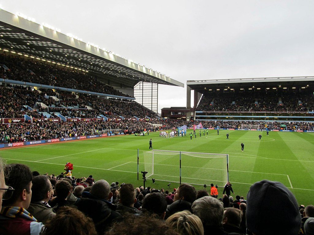 Fans watch from the stands as players line up on the pitch at Villa Park