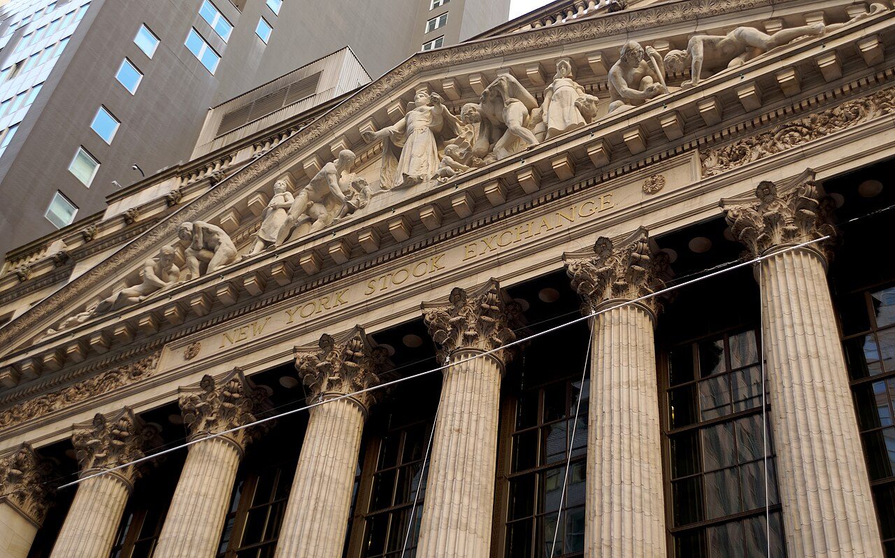 The columned facade of the New York Stock Exchange, with carved figures in the pediment above the words New York Stock Exchange, seen from below
