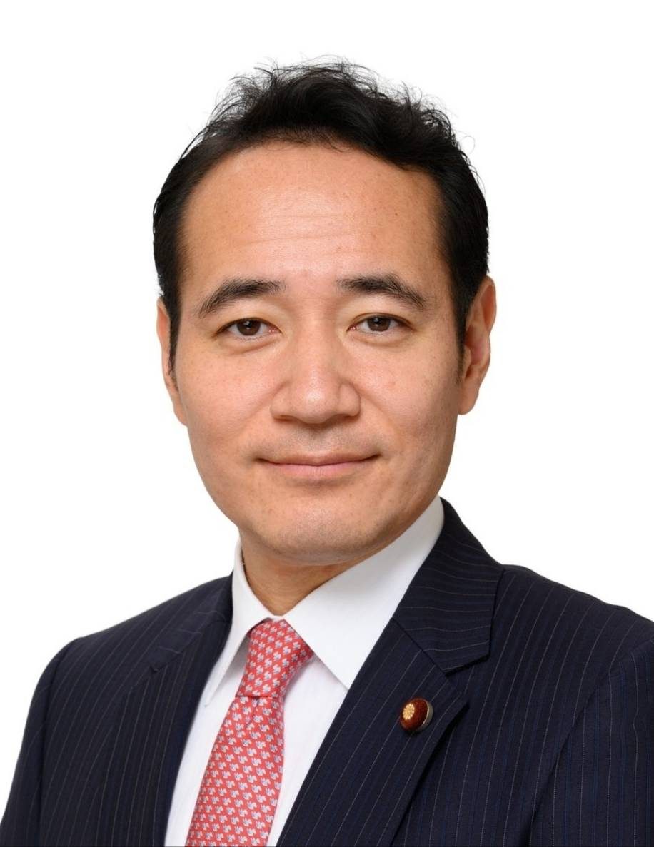 Official portrait of Kazuo Yana in a dark suit and pink tie against a white background