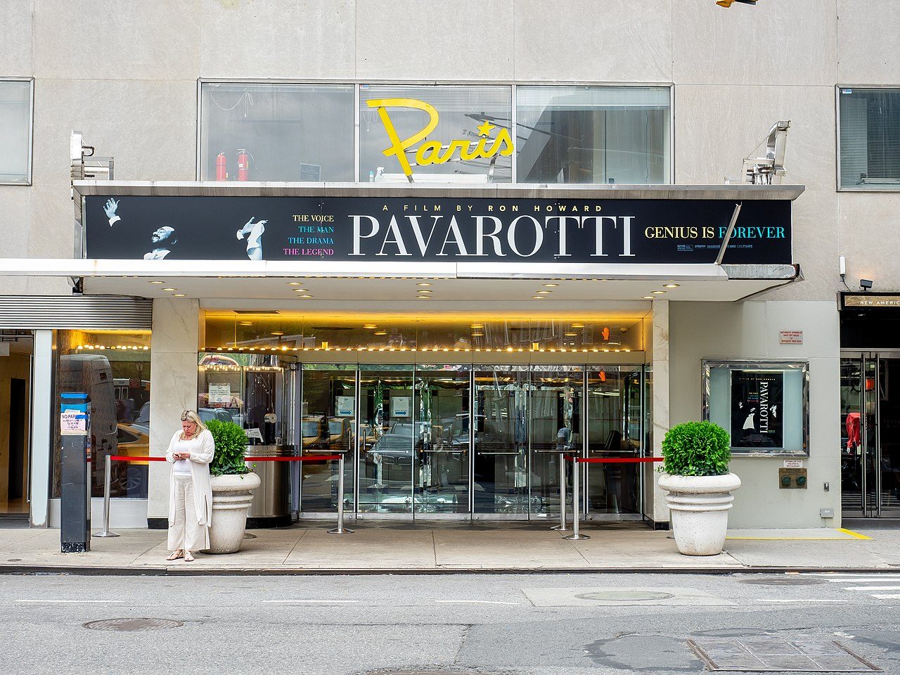 The entrance of the Paris Theater in Midtown Manhattan, with a marquee advertising a Pavarotti film