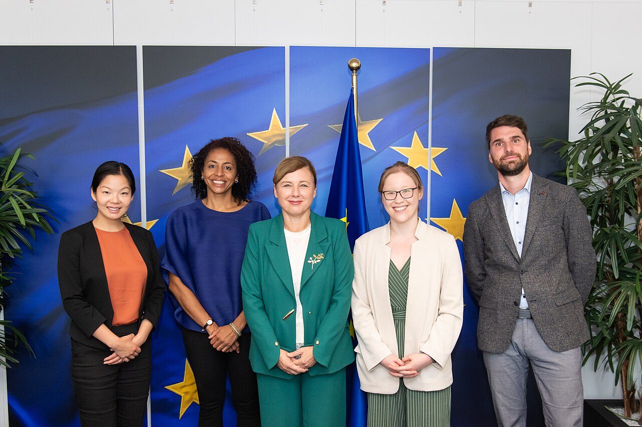 Five people pose in front of European Union flags during a visit by OpenAI representatives to the European Commission