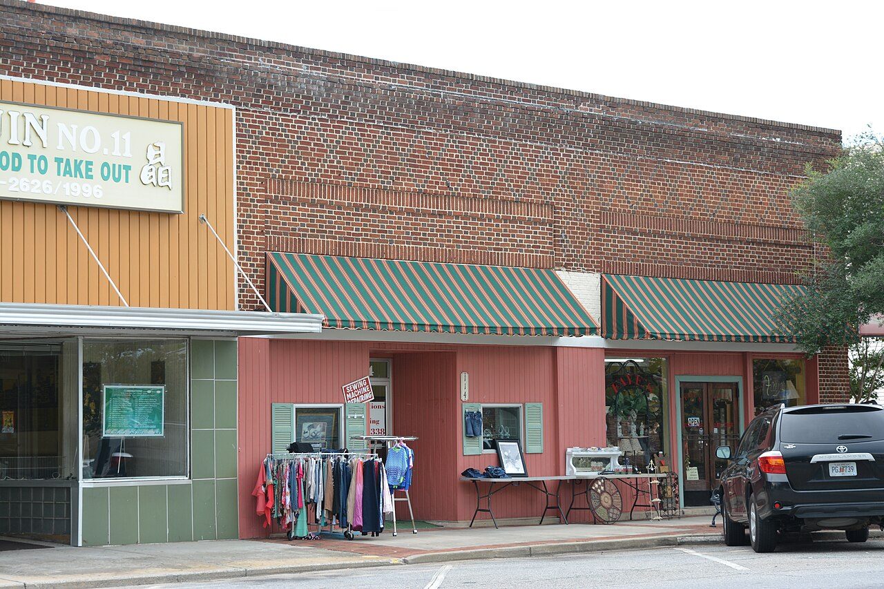 A row of low brick storefronts with awnings along a quiet downtown street