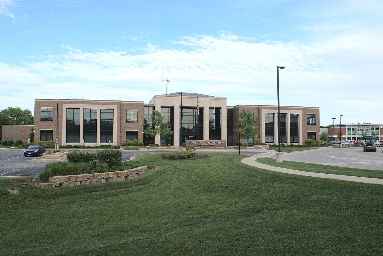 A two-story brick and glass police headquarters building with a lawn in front