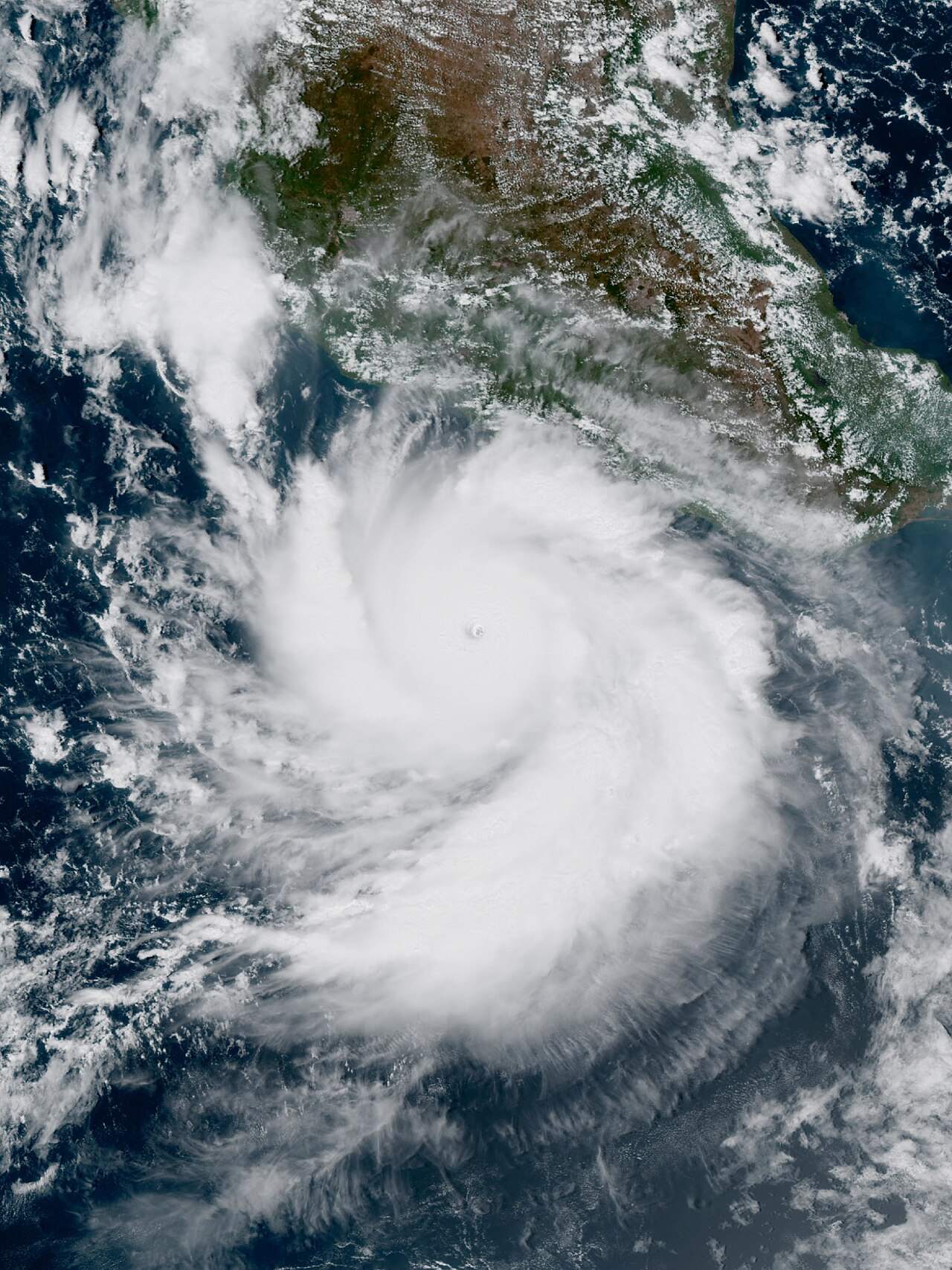 Satellite view of a large hurricane with a clear eye over the ocean near a coastline