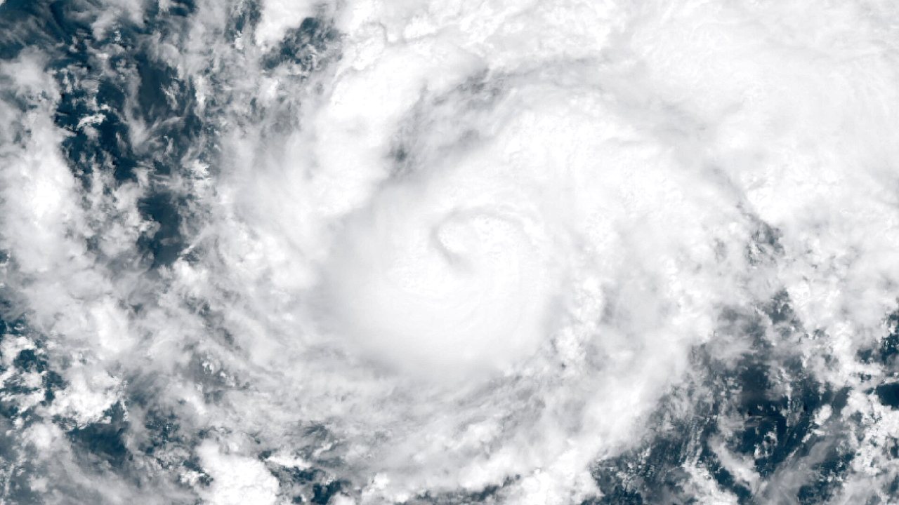 Satellite view of Hurricane Trudy, a large white spiral of cloud with a small eye near its center, over the dark blue Pacific Ocean