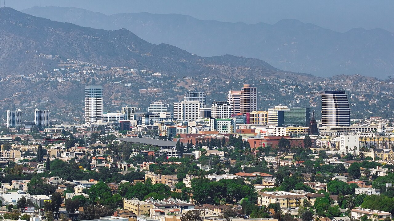 Downtown high-rise buildings among trees and houses, with hazy mountains behind