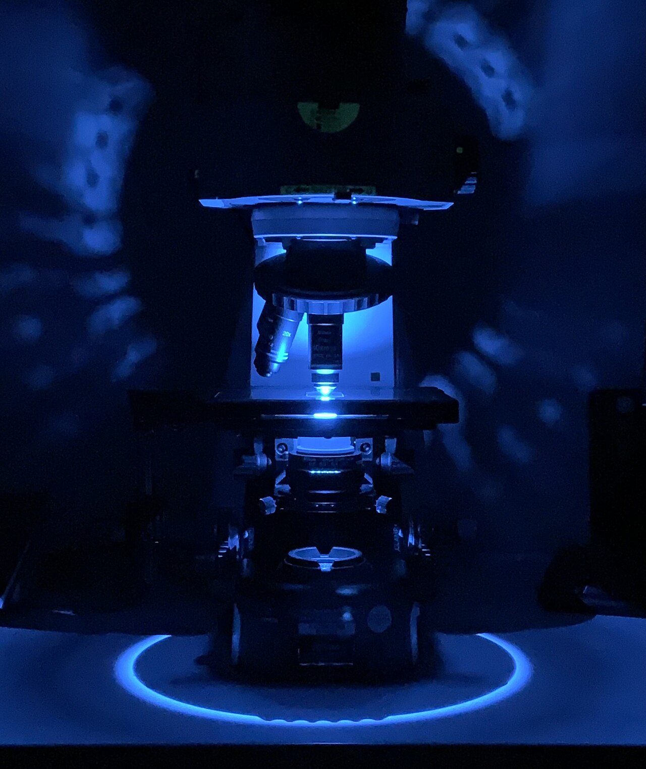 A microscope glowing with blue light against a dark background
