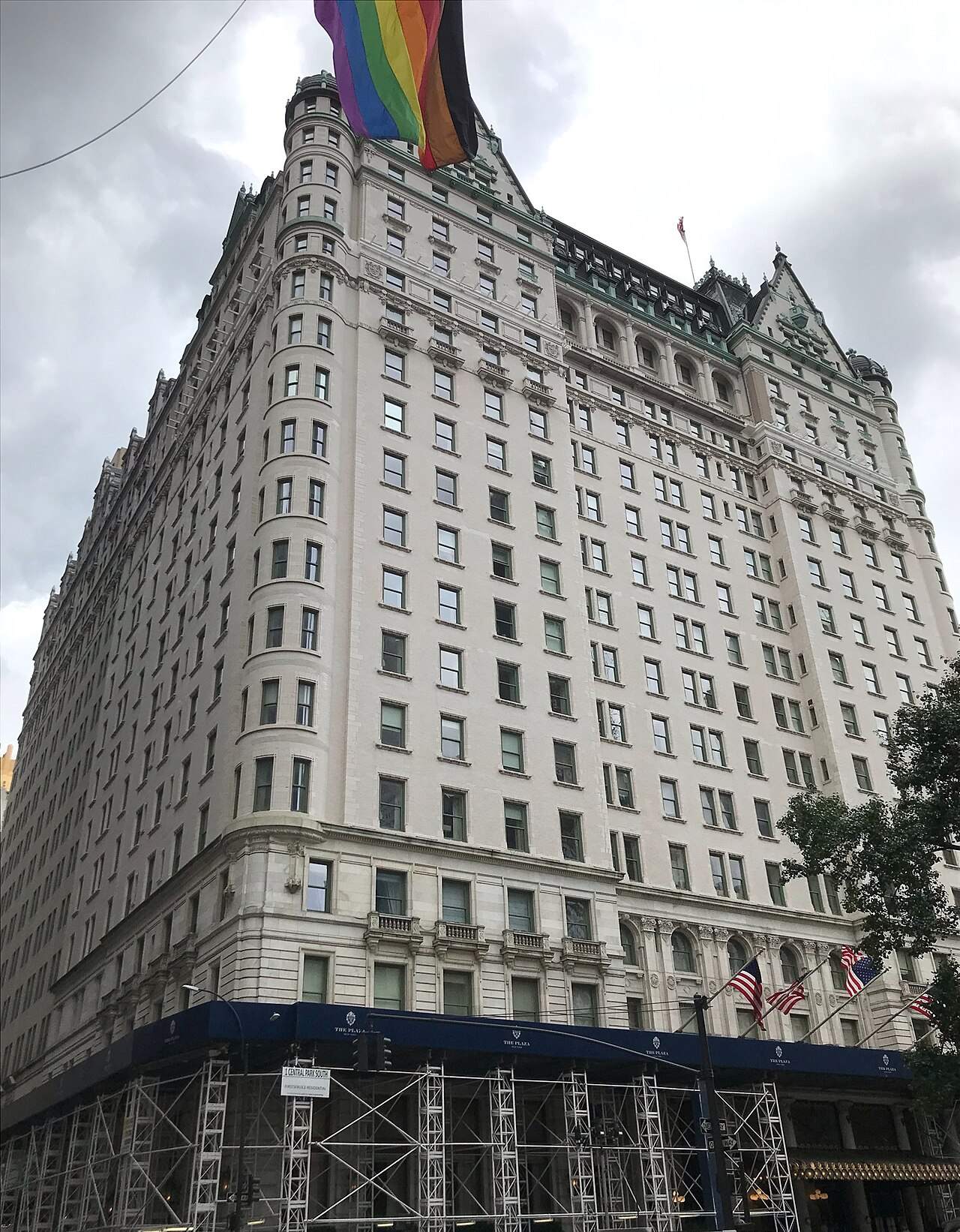 The tall white Plaza Hotel building with dark blue scaffolding around its lower floors