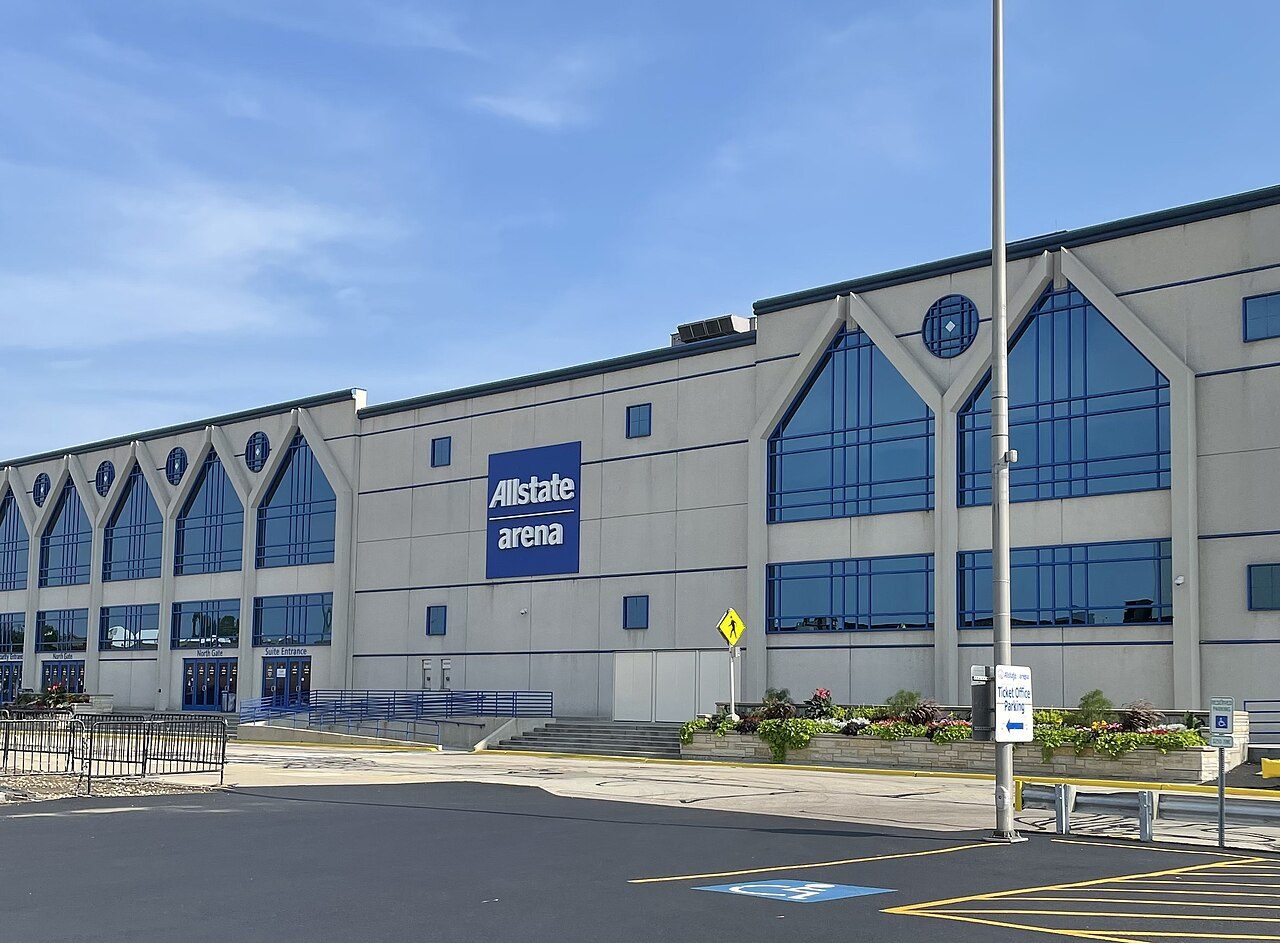 The gray exterior of Allstate Arena with blue windows and an empty parking lot