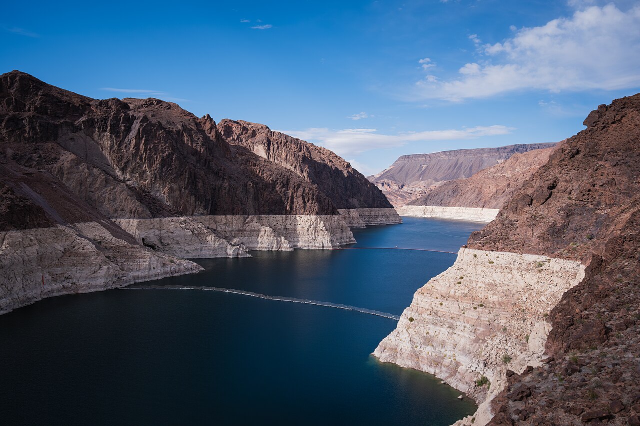 Deep blue water of Lake Mead in a rocky canyon, with a wide white band of mineral-stained rock above the waterline on both sides