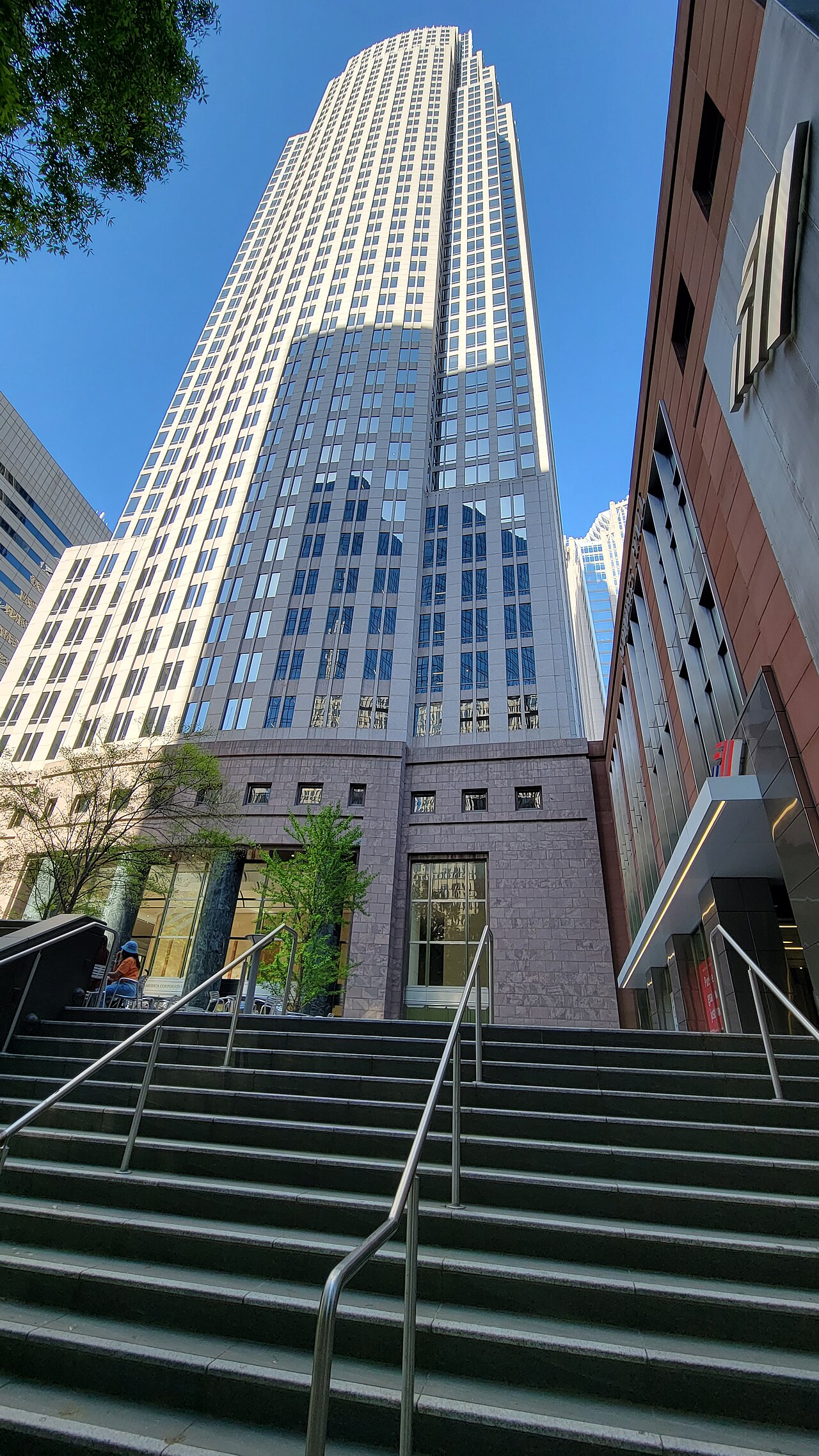 The Bank of America Corporate Center skyscraper in Charlotte seen from the bottom of a wide stone staircase on a sunny day
