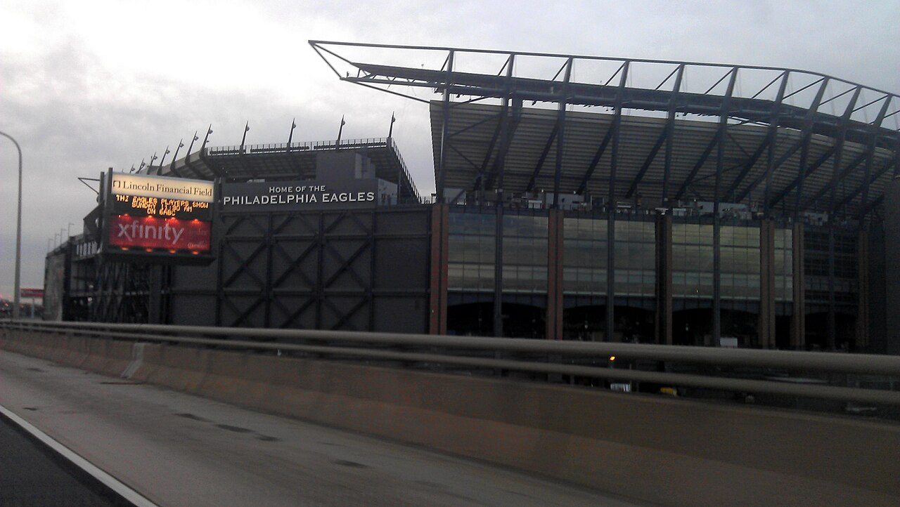 The outside of Lincoln Financial Field under a gray sky, with a sign reading "Home of the Philadelphia Eagles" and a video board