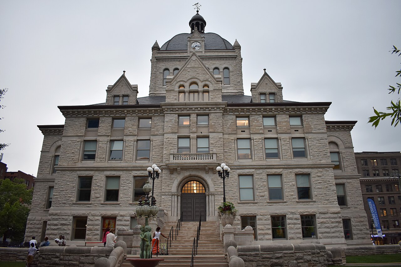 The Old Fayette County Courthouse in Lexington, a pale stone building with a central clock tower and dome, with people on the steps outside