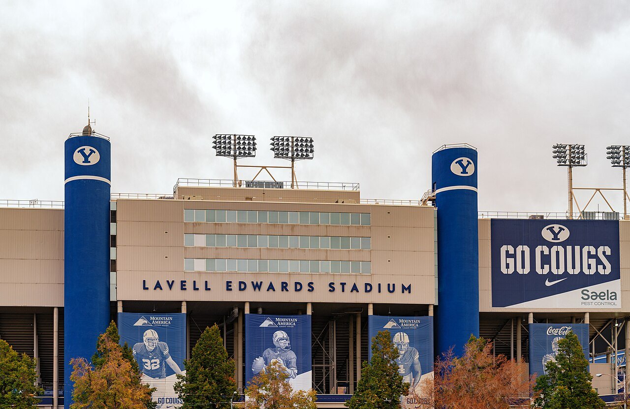 The exterior of LaVell Edwards Stadium in Provo, Utah, with blue BYU light towers, player banners and a Go Cougs sign