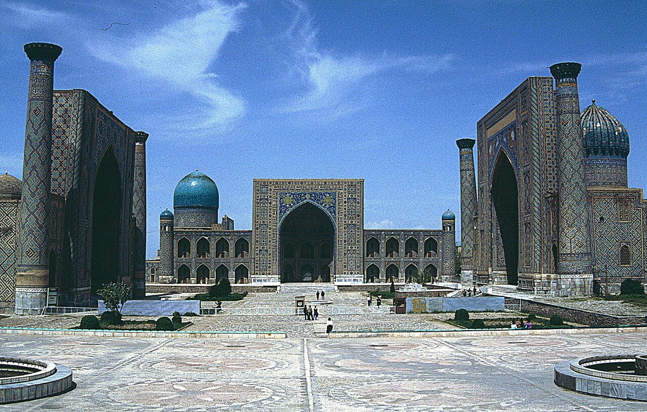 The Registan square in Samarkand, with three tiled madrasas and blue domes under a blue sky