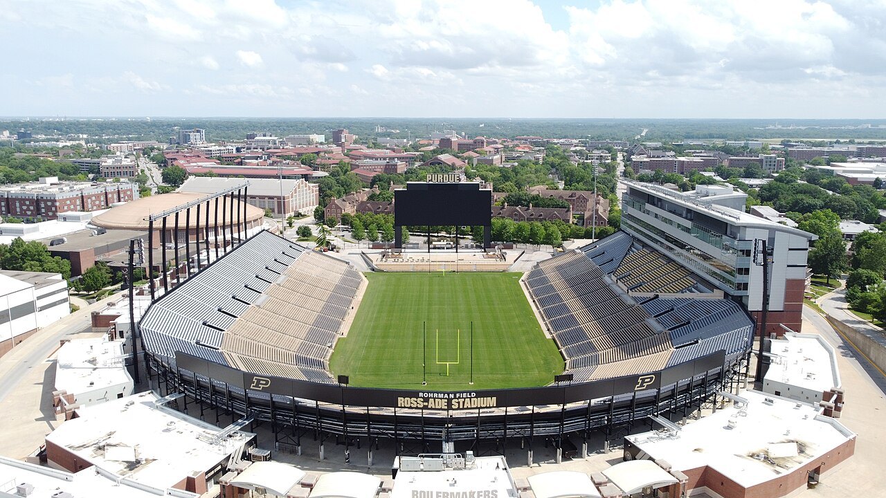 Aerial view of Ross-Ade Stadium at Purdue University, with a green football field, grandstands and campus buildings around it