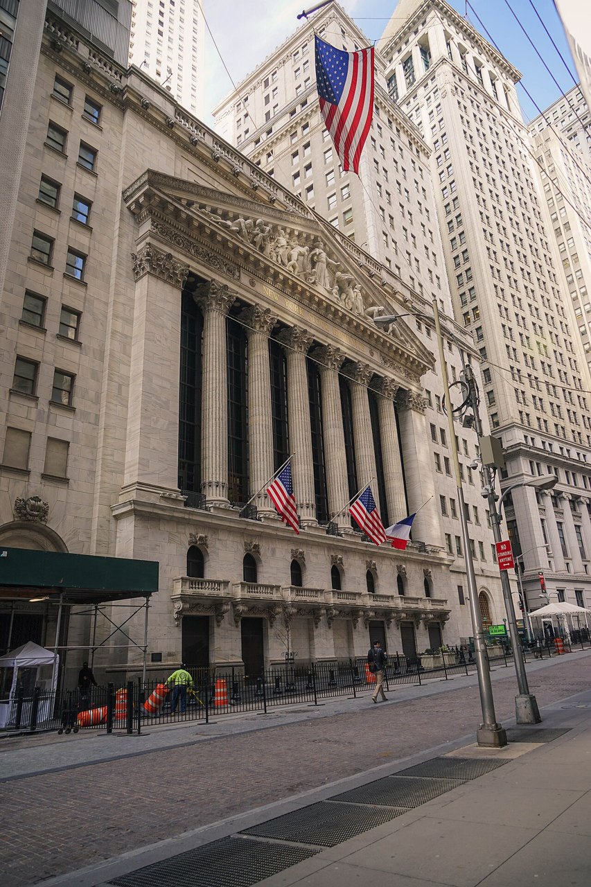The columned facade of the New York Stock Exchange with a large American flag
