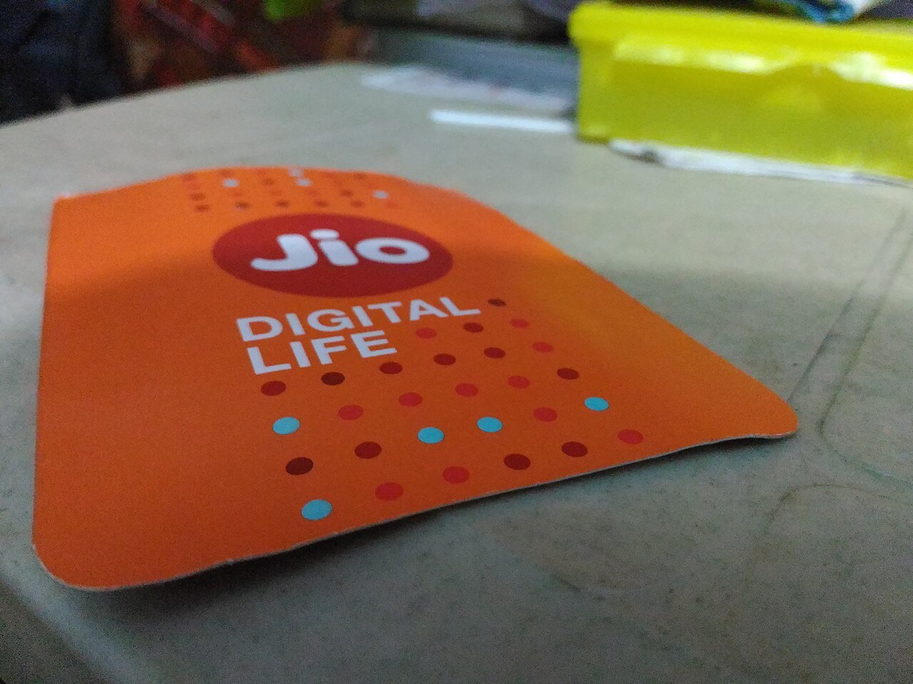 An orange Jio Digital Life SIM card holder lying on a table
