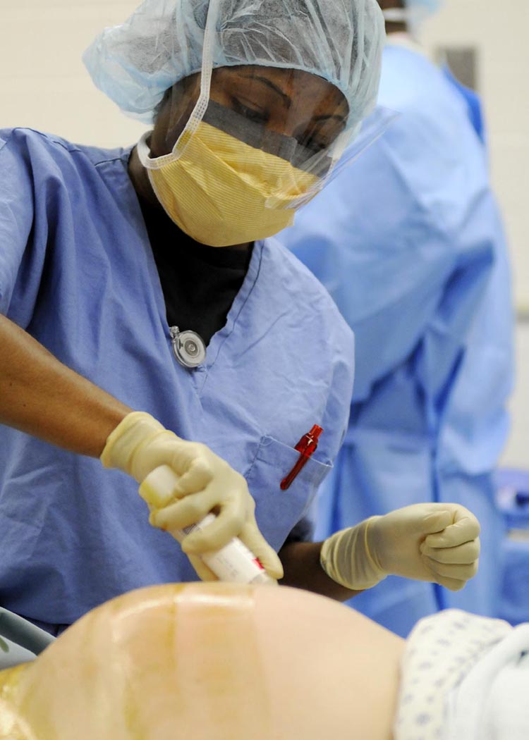 A nurse in a surgical cap and mask cleans a pregnant woman's belly in an operating room before a Caesarean delivery