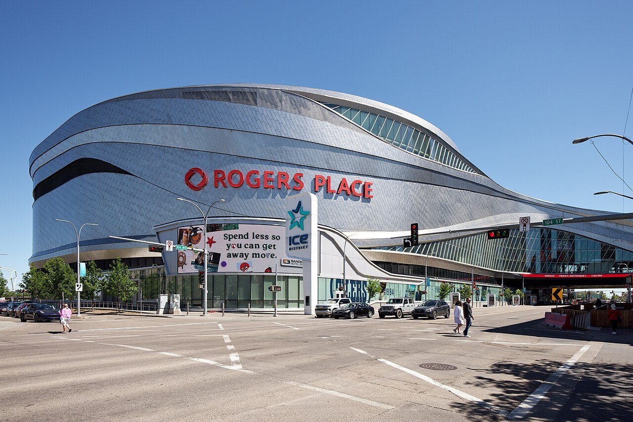 The curved silver exterior of Rogers Place arena in Edmonton on a sunny day, with a street in front