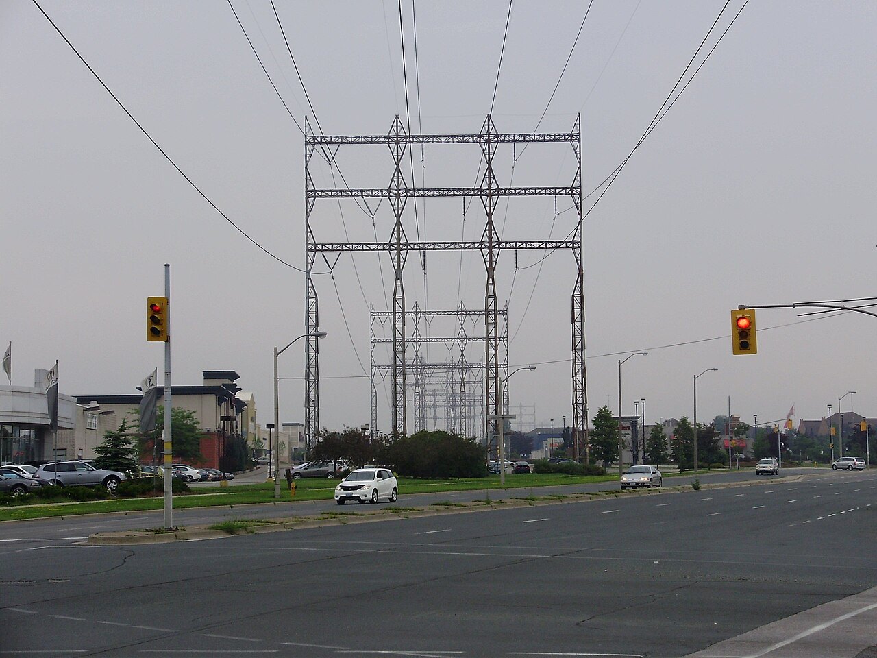 Steel transmission towers and power lines crossing a wide road intersection