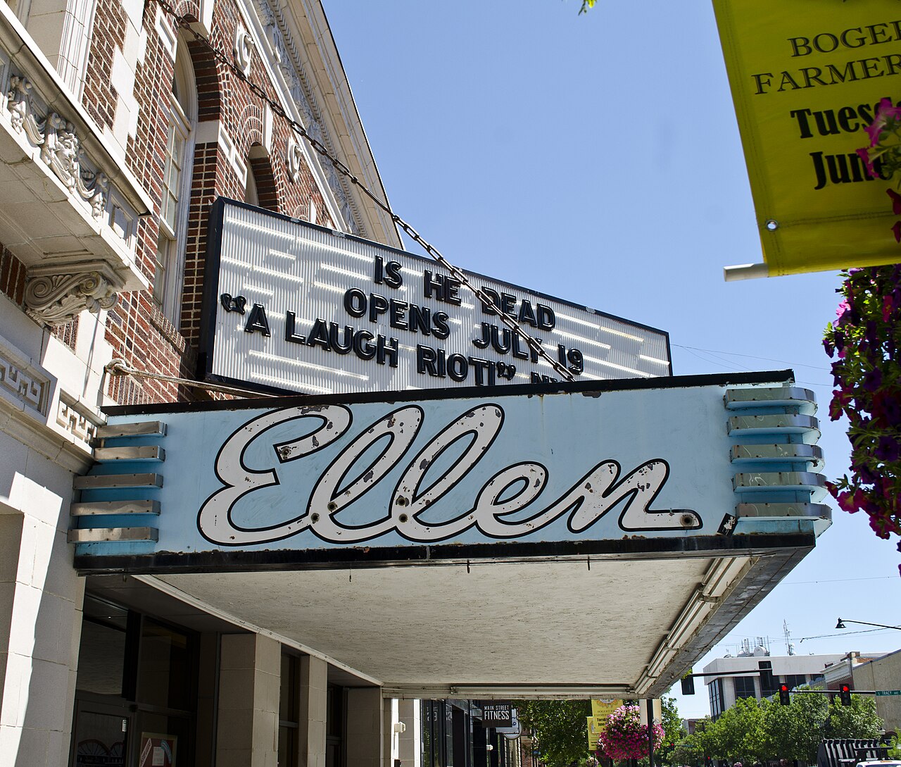 The blue and white Ellen sign on the marquee of a historic brick cinema, with a letter board above it and a street behind