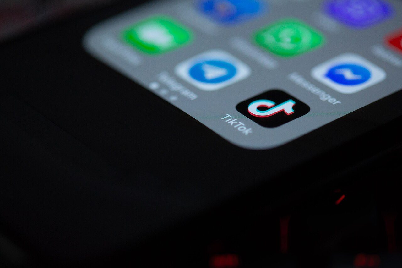 Close-up of a smartphone home screen showing app icons, with the black TikTok music-note icon in the center