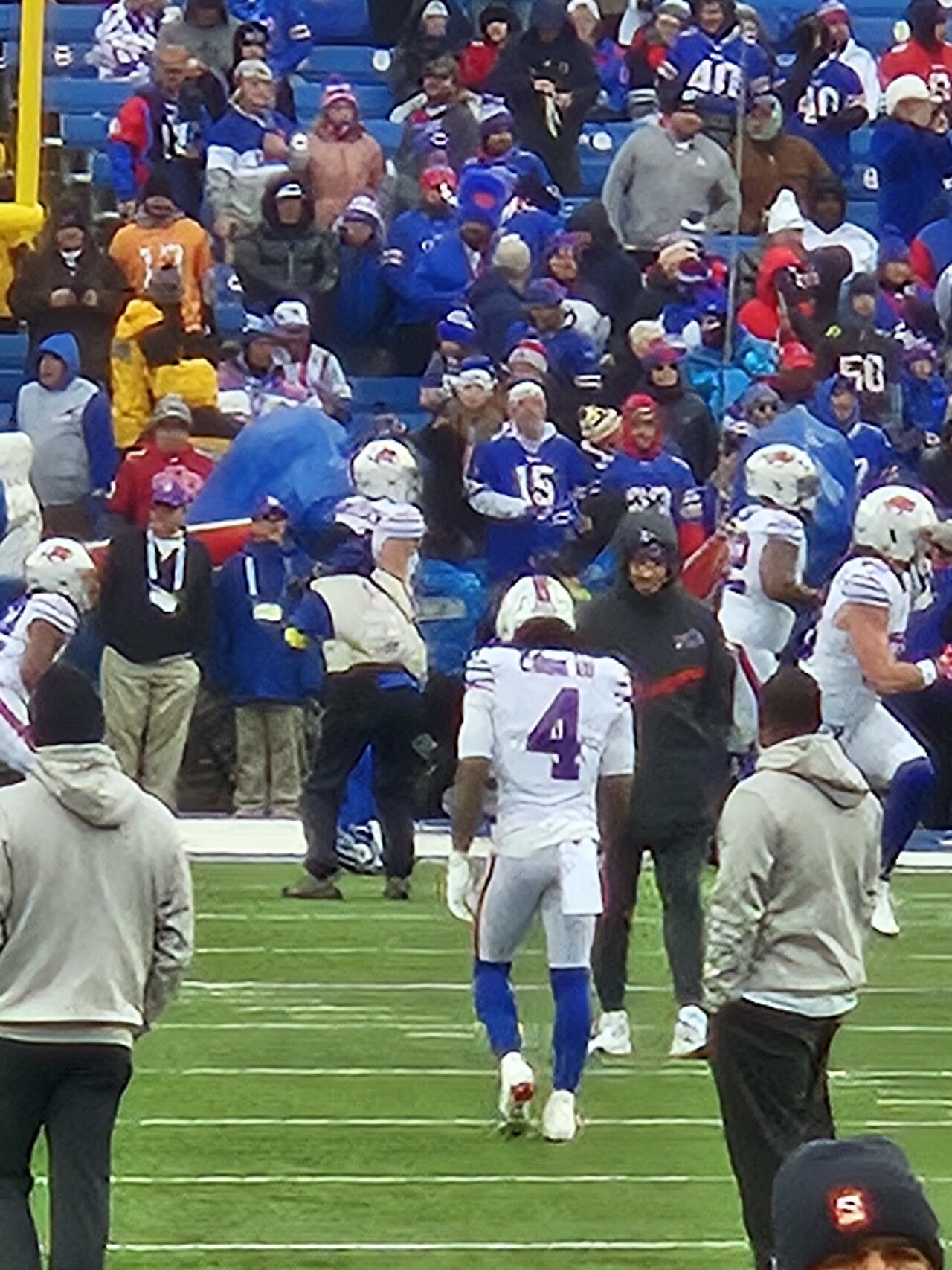 A Buffalo Bills player wearing number 4 walks on the field in front of a crowd of fans in blue and red
