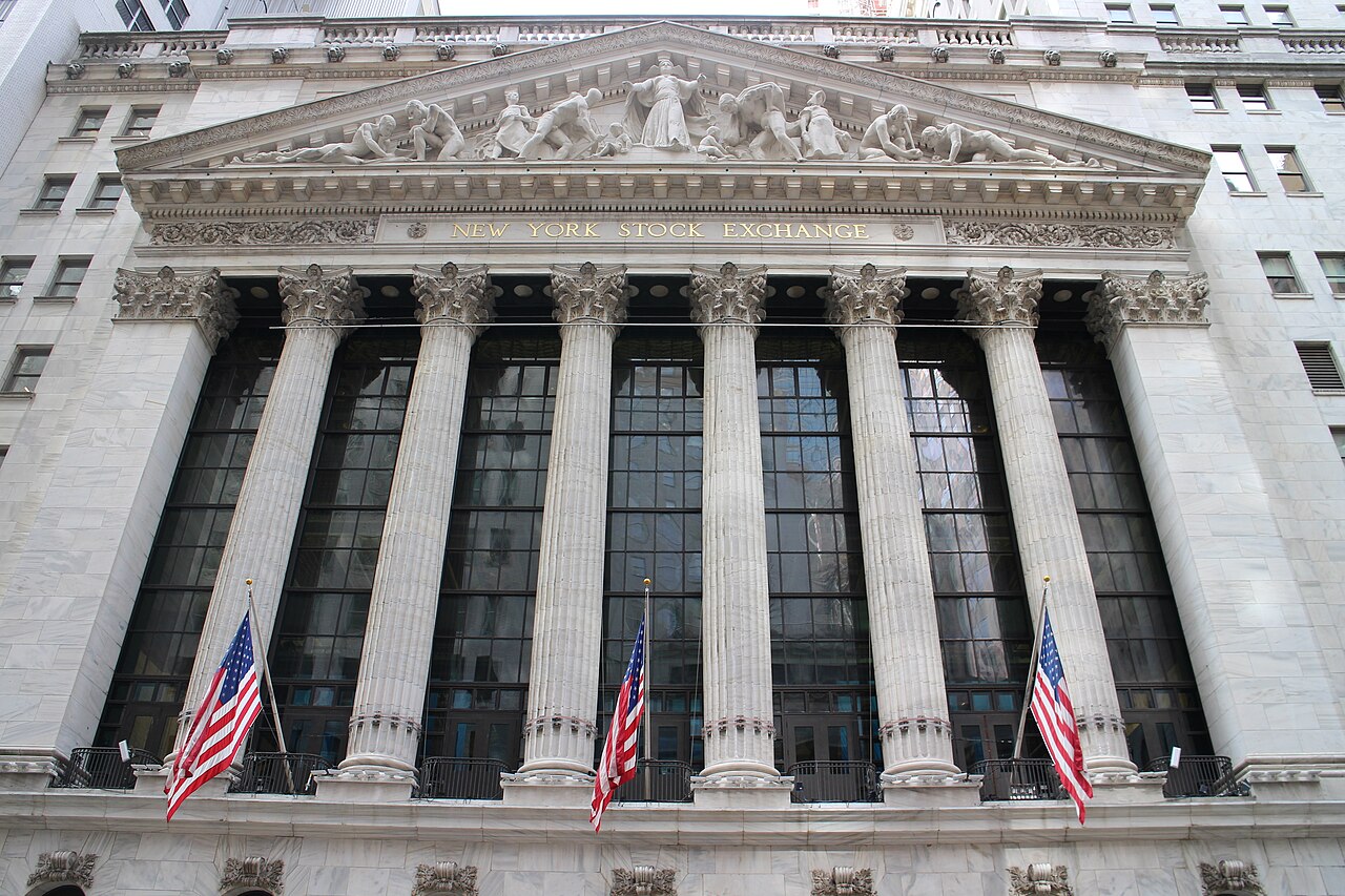 The columned marble front of the New York Stock Exchange building with American flags hanging between the columns