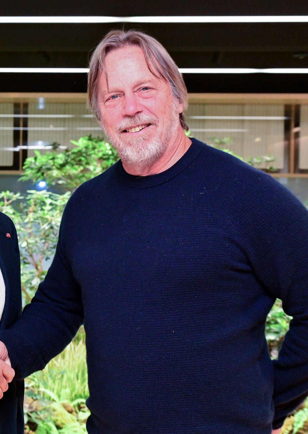 Jim Keller in a dark jacket standing indoors during a business meeting