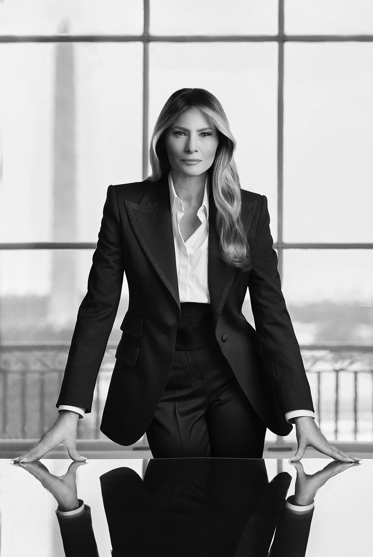 Formal portrait of a woman in a dark suit standing in front of a window