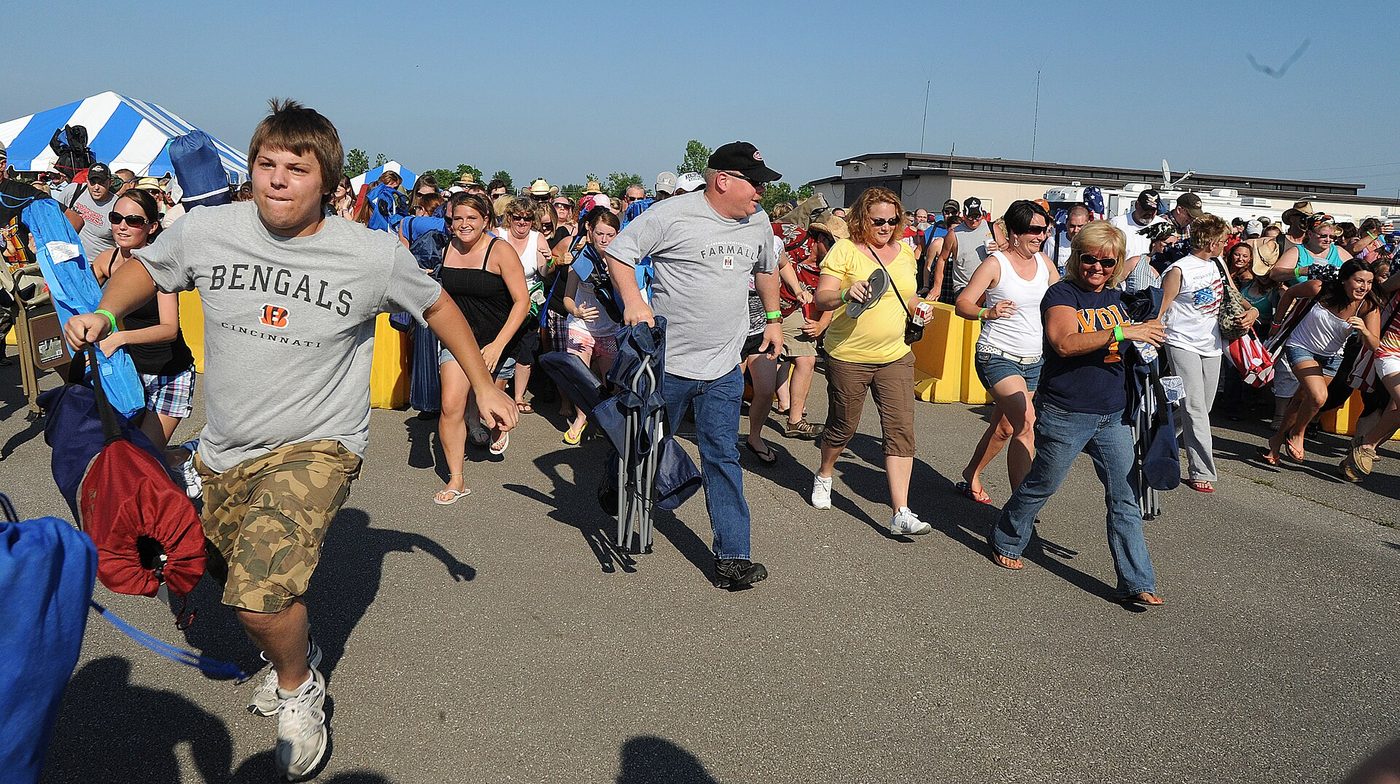 A crowd of concertgoers rushing toward an outdoor stage