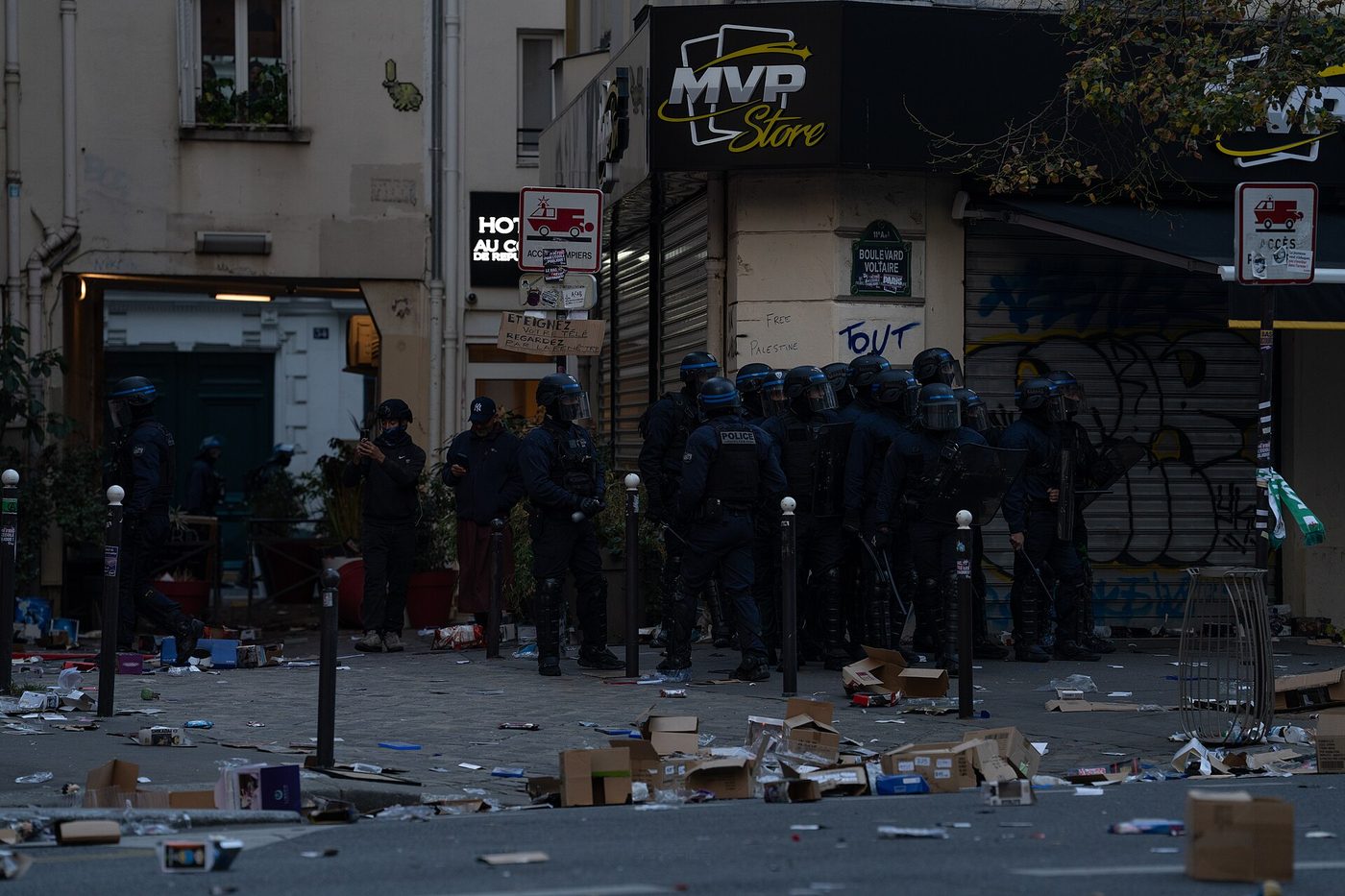 Riot police in protective gear standing outside a looted shop in Paris