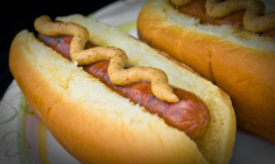 Grilled hot dogs in buns topped with mustard